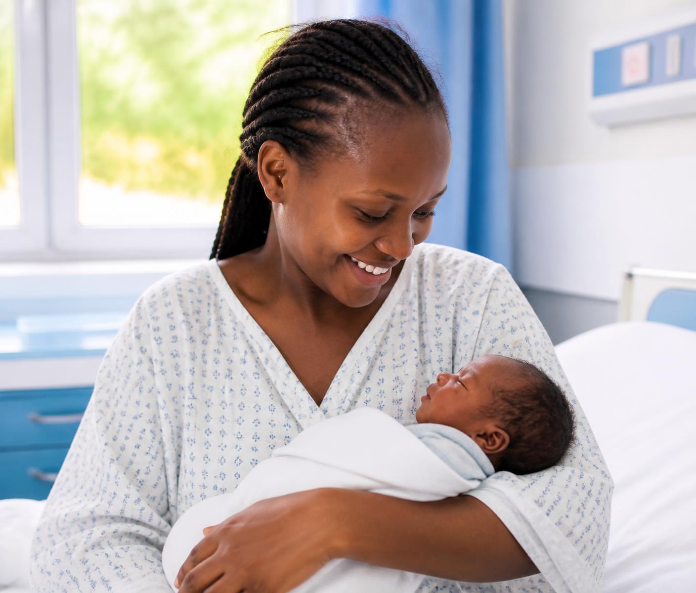 A mother holding her newborn baby in a maternity room